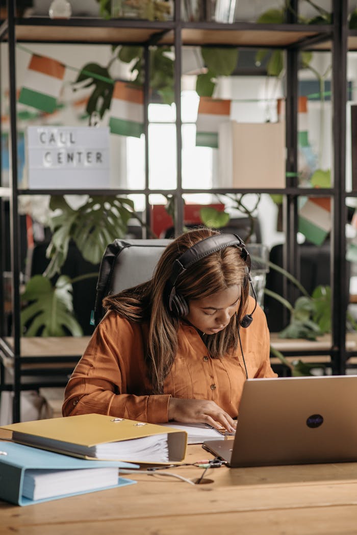 A dedicated call center agent wearing headphones works at her desk in a vibrant office space.